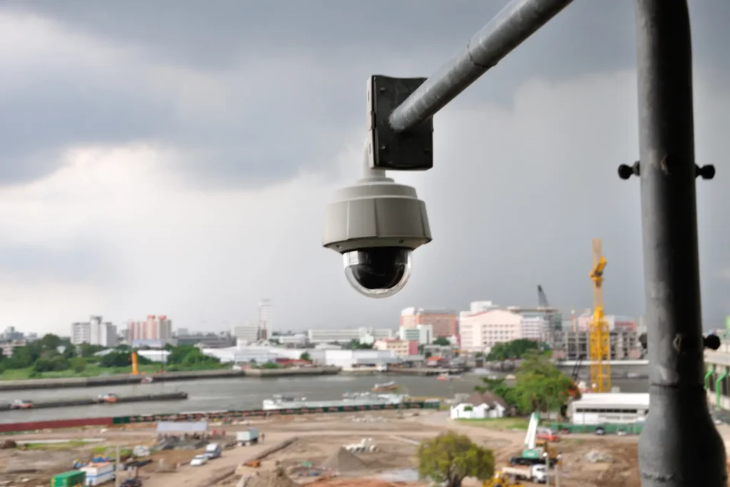 Eine Ueberwachungskamera haengt an einem hohen Laternenmast und dokumentiert den Baufortschritt